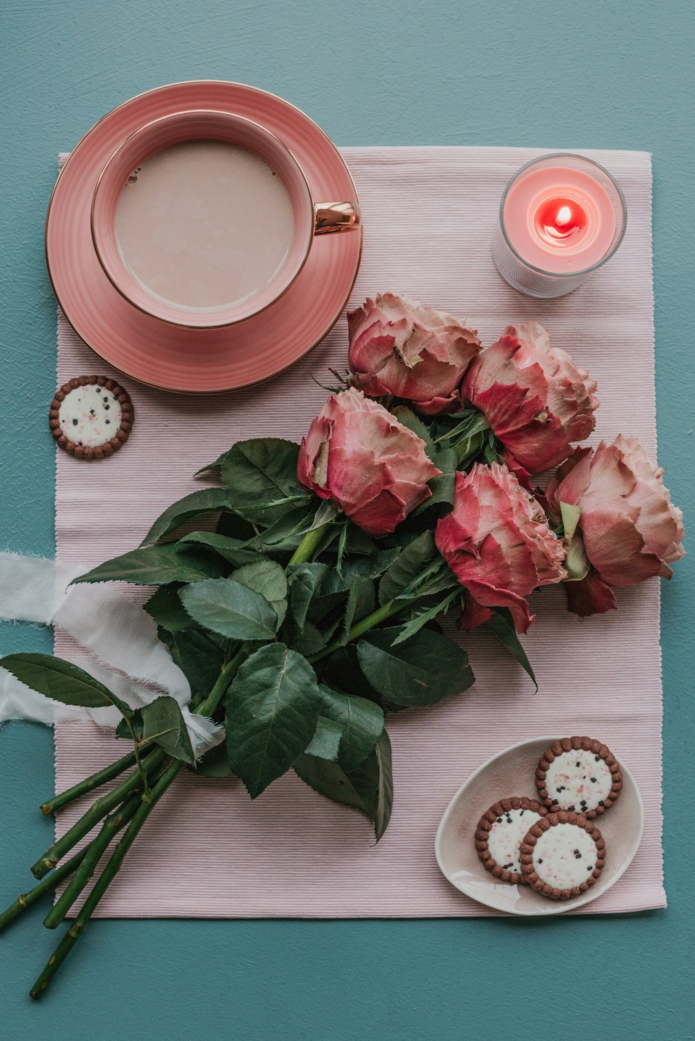 a table topped with pink flowers next to a cup of coffee