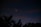 A nighttime sky features two bright celestial objects, likely planets or stars, shining through a dark backdrop. Silhouetted tree tops are visible at the bottom, creating a natural frame for the serene astronomical scene.