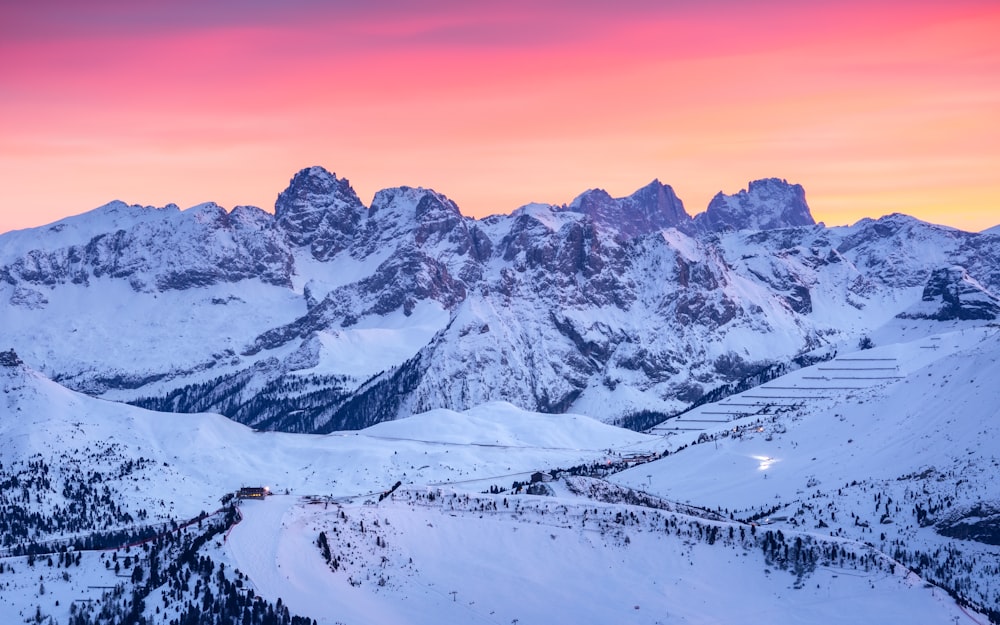 a mountain range covered in snow at sunset