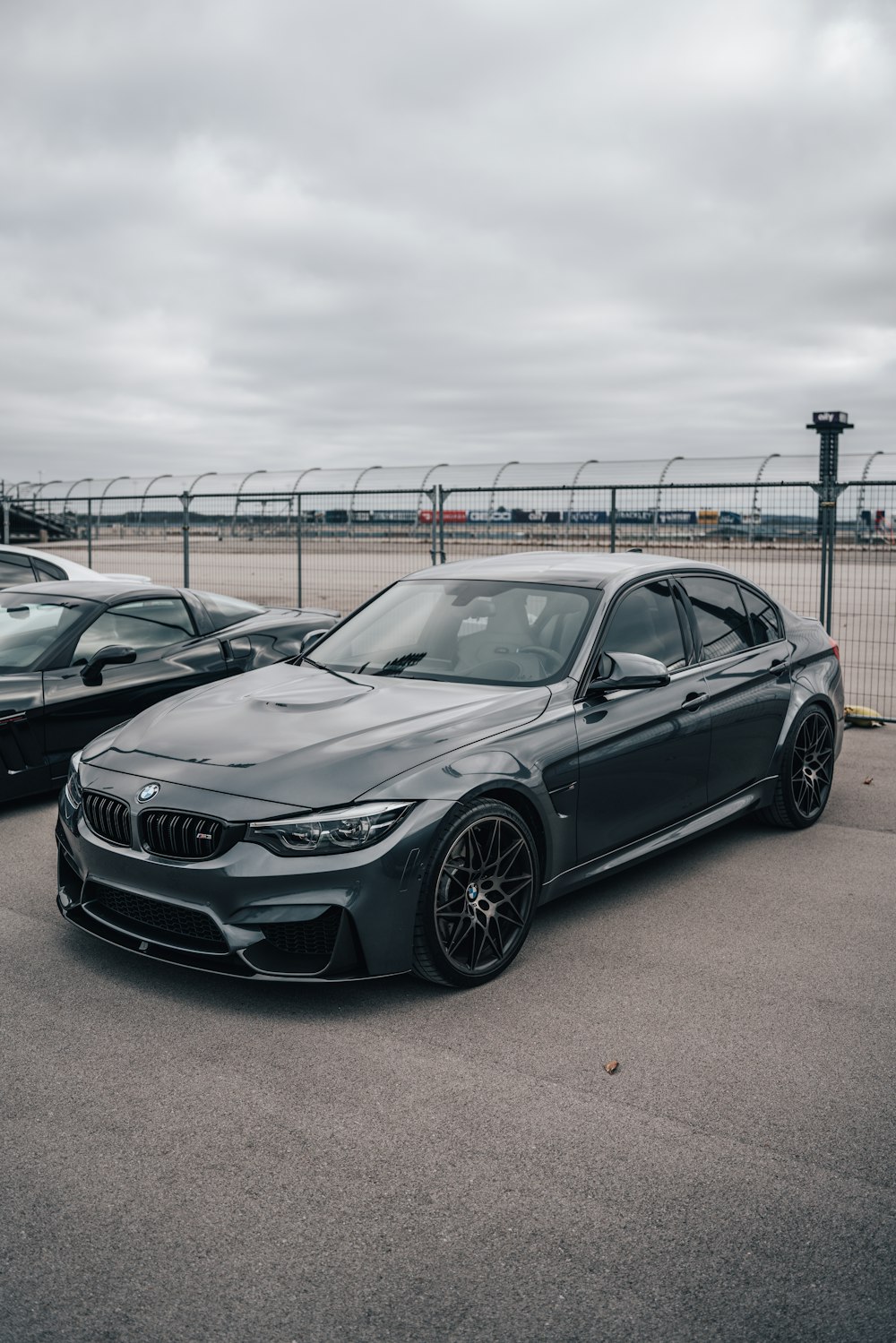 a grey car parked in a parking lot next to a fence