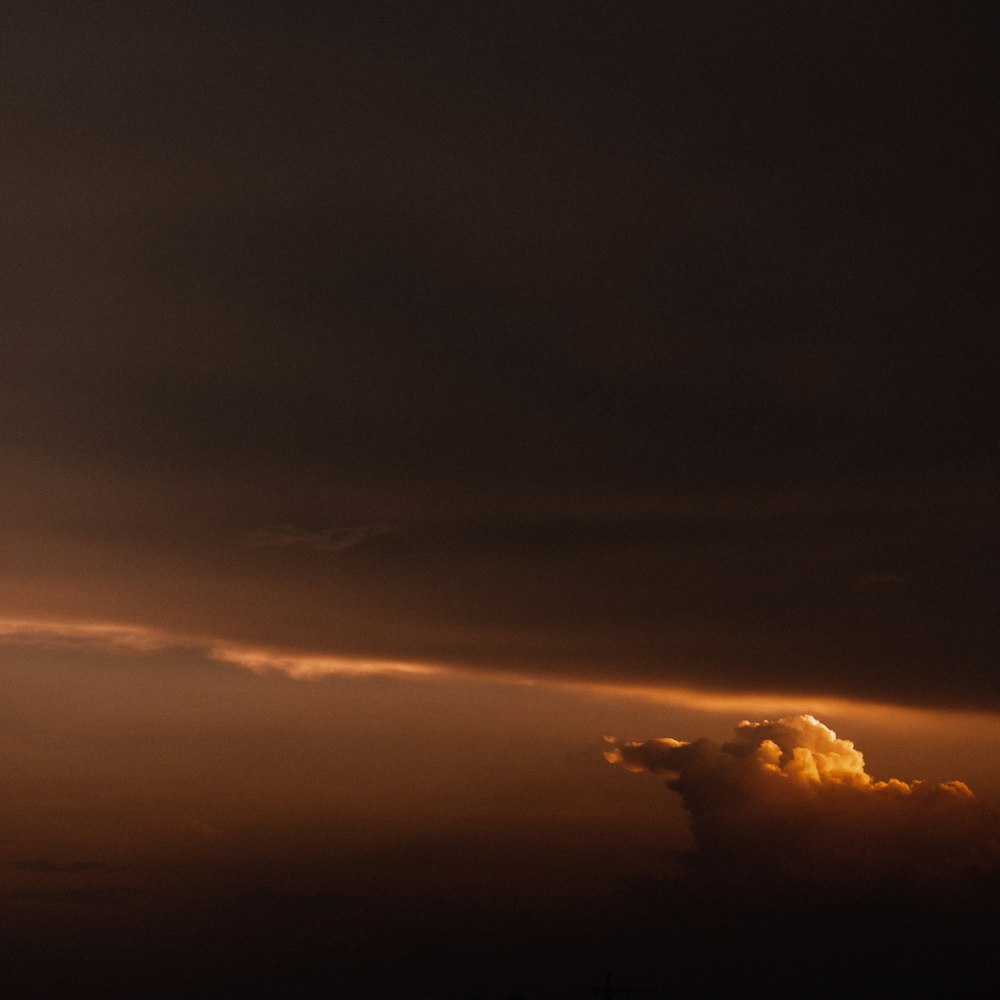 a plane flying through a cloudy sky at sunset