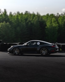 A dynamic shot of a Porsche 911 cruising along the Nurburgring track on a sunny day.