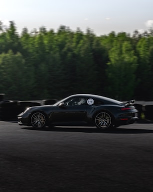 A dynamic shot of a Porsche 911 cruising along the Nurburgring track on a sunny day.
