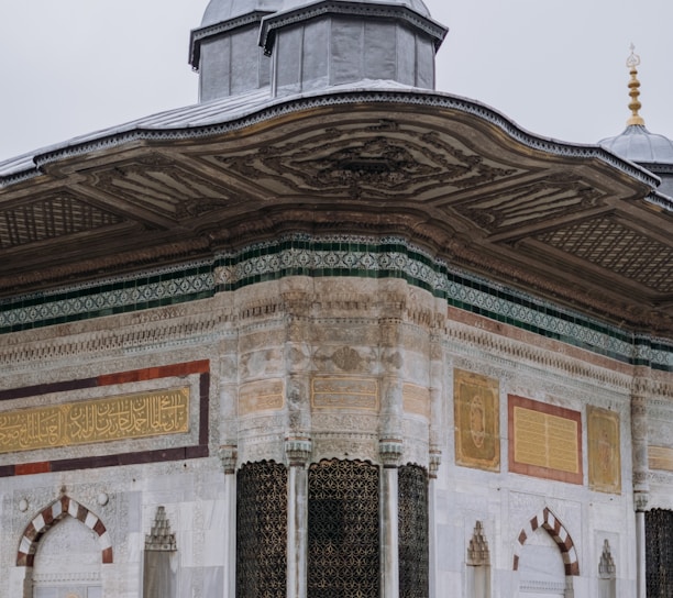 a white building with a black roof and two gold domes