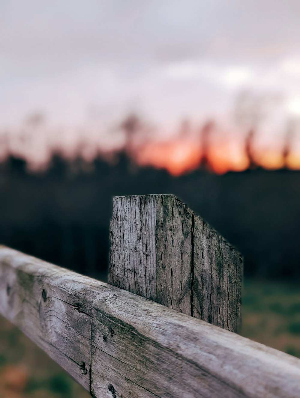 a close up of a wooden fence with a sunset in the background