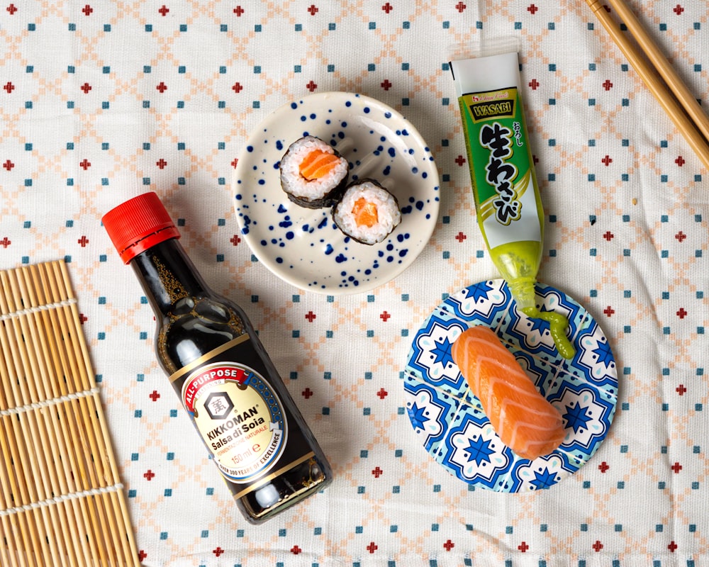 a table topped with a plate of sushi and a bottle of sauce