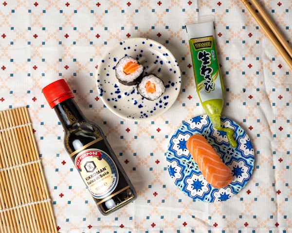 A table topped with a plate of sushi and a bottle of sauce