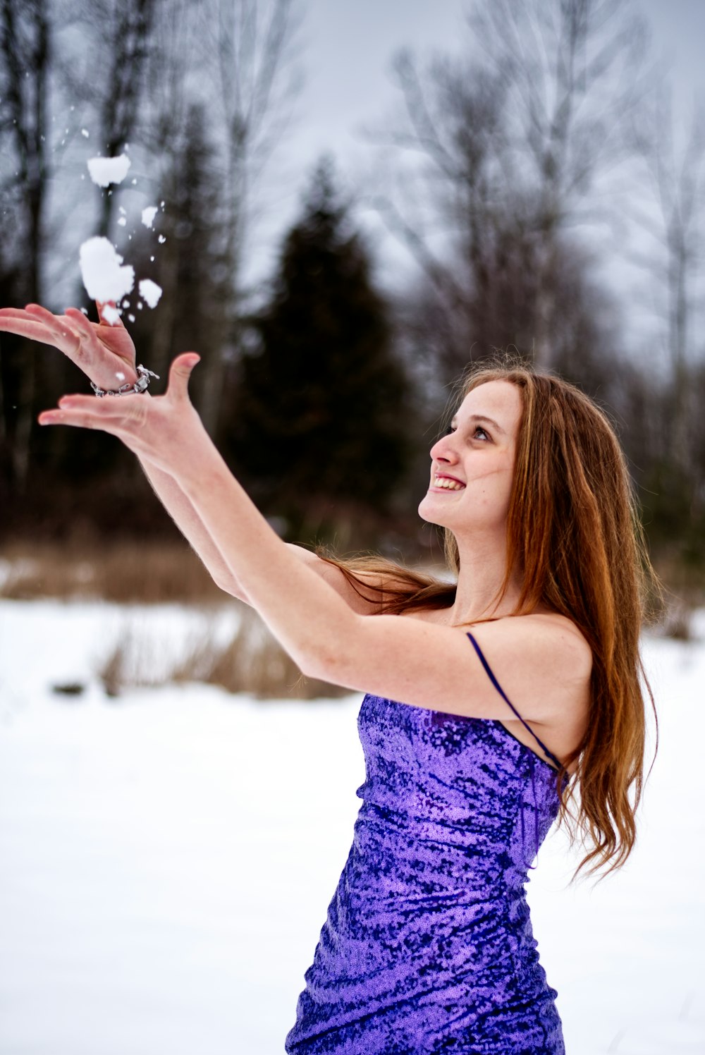 a woman in a purple dress throwing snow into the air