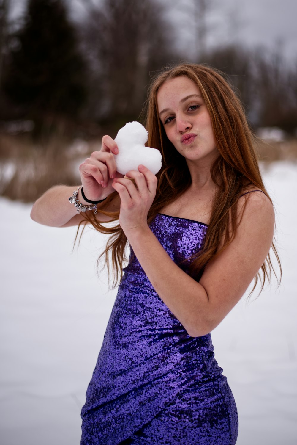 a woman in a purple dress holding a snowball