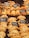 An assortment of baked pastries and empanadas on display with labels indicating different types and prices. The pastries are neatly arranged in rows, showcasing various fillings and crusts. The warm lighting emphasizes the golden-brown color of the baked goods.