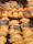 An assortment of baked pastries and empanadas on display with labels indicating different types and prices. The pastries are neatly arranged in rows, showcasing various fillings and crusts. The warm lighting emphasizes the golden-brown color of the baked goods.