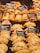 An assortment of baked pastries and empanadas on display with labels indicating different types and prices. The pastries are neatly arranged in rows, showcasing various fillings and crusts. The warm lighting emphasizes the golden-brown color of the baked goods.
