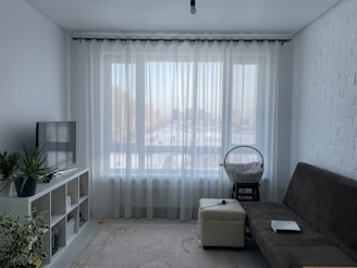 Modern living room with large windows covered by elegant curtains.