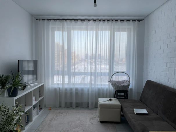 A modern living room with sleek white stor curtains filtering soft daylight.