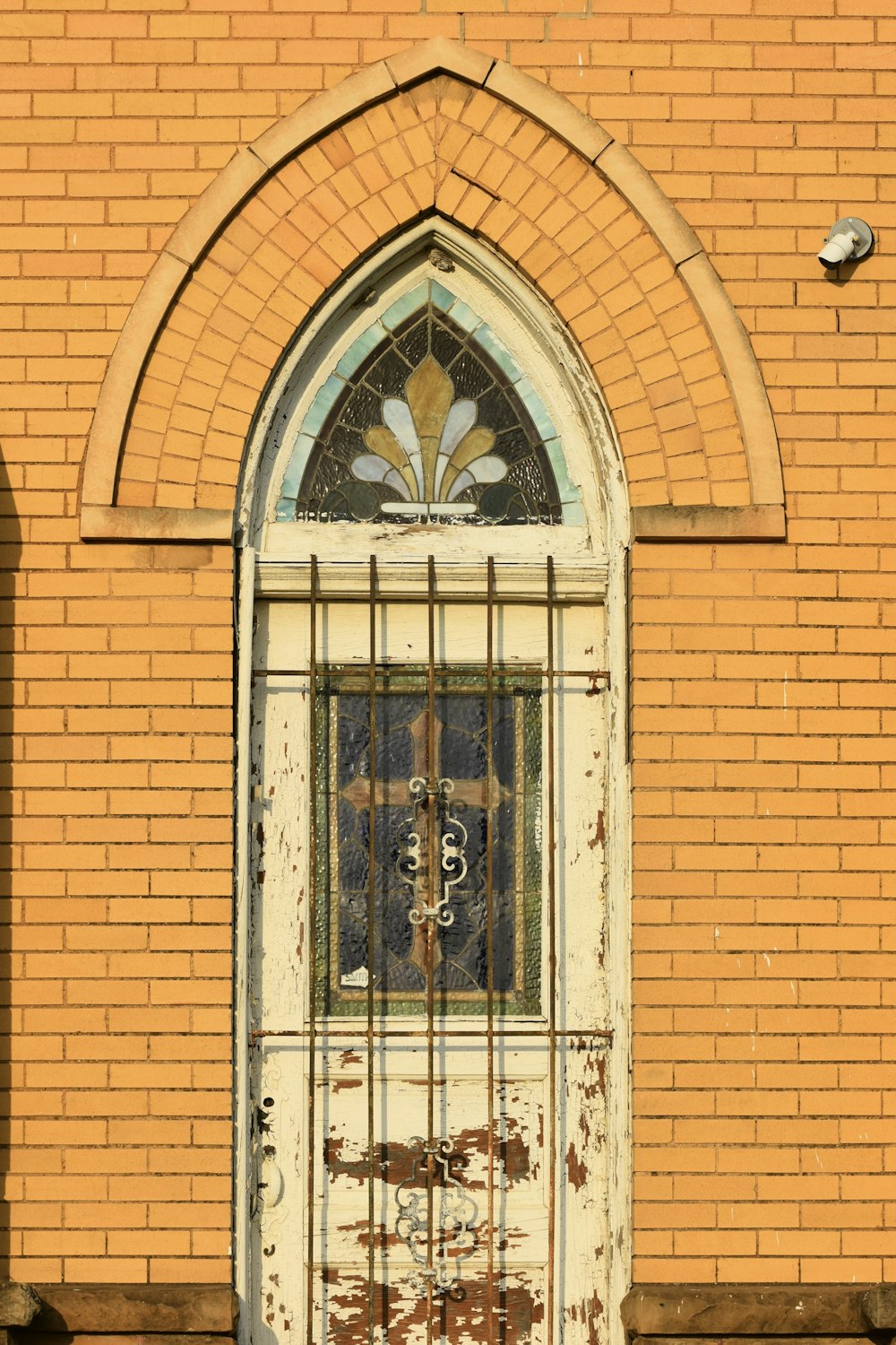 an old door with a window and bars in front of a brick building