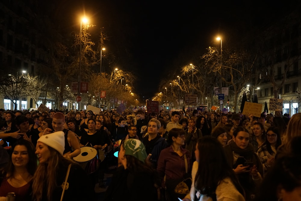 a large group of people standing on a street at night
