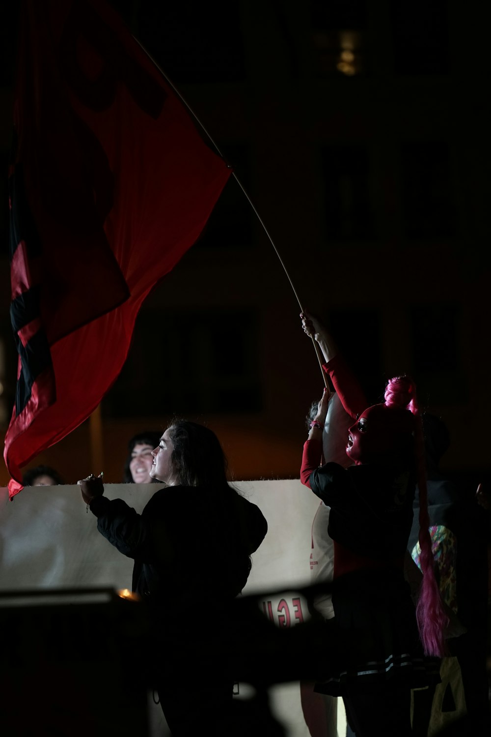 a group of people holding a red and black flag
