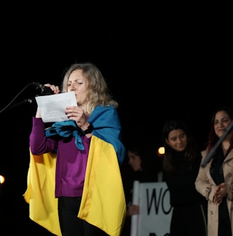 a woman standing in front of a microphone holding a piece of paper