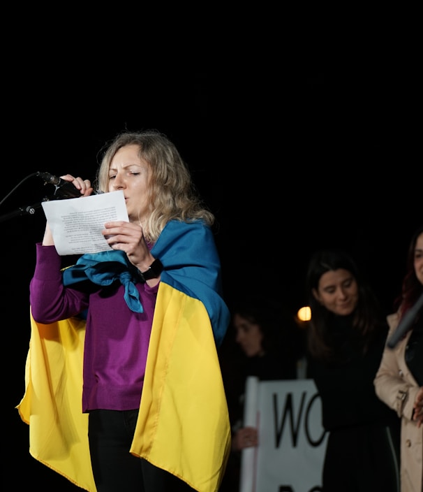 a woman standing in front of a microphone holding a piece of paper