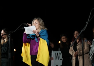 a woman standing in front of a microphone holding a piece of paper