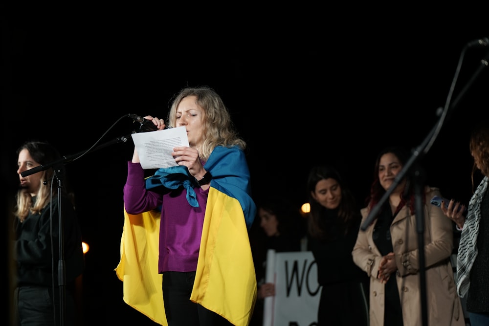 a woman standing in front of a microphone holding a piece of paper