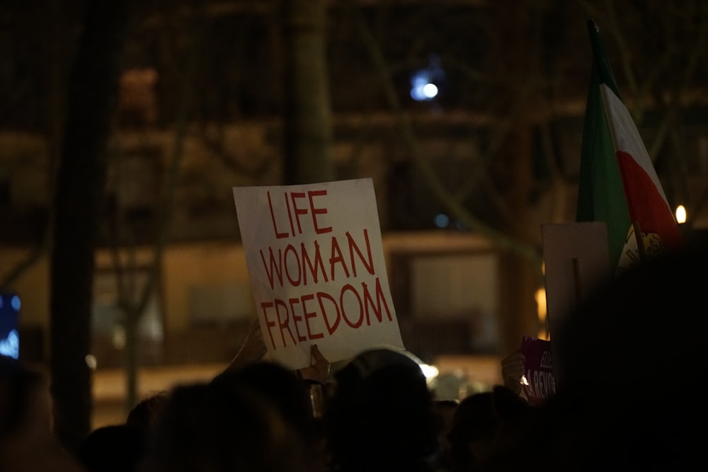 a person holding a sign that says life woman freedom