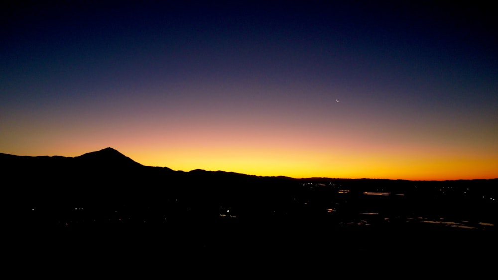 the sun is setting over a mountain range