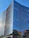 A sleek modern office building with reflective glass windows under a clear blue sky.