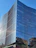 A sleek modern office building with reflective glass windows under a clear blue sky.