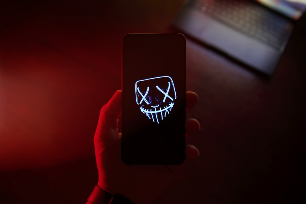 a person holding a cell phone with a scary face on it
