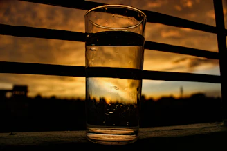 A peaceful morning scene with a glass of water and glucavit supplement next to a sunrise window.