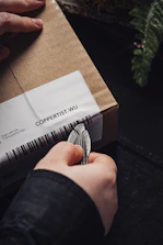 Close-up of a hand peeling off a barcode label inside a warehouse.