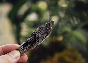 Hand holding a finely crafted small metal ornament with precise edges.