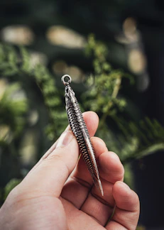 Close-up of a hand-crafted sterling silver fish with articulated fins shimmering under soft light.