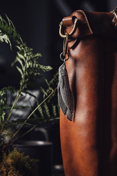 A colorful handmade keychain hanging from a leather bag strap, showcasing playful details.