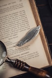 Close-up of an open novel with a vintage bookmark resting on the pages.