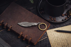 A stylish clavea key pouch sitting next to a cup of coffee and a notebook on a café table