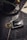 A detailed car key fob with a decorative feather-shaped keychain attached is positioned on a rustic wooden surface. Coffee beans are scattered nearby, with a dark, textured coffee cup and saucer in the background. A handwritten note and pen add to the cozy, vintage atmosphere.