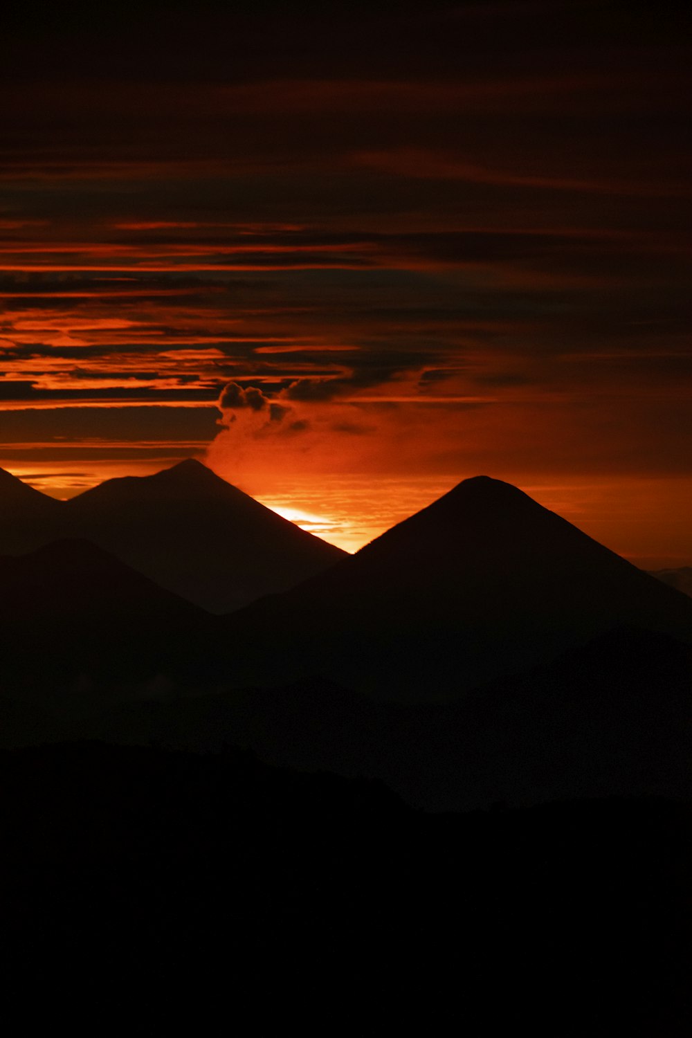 the sun is setting over a mountain range