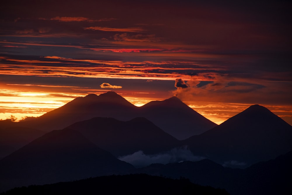 the sun is setting over the mountains in the distance