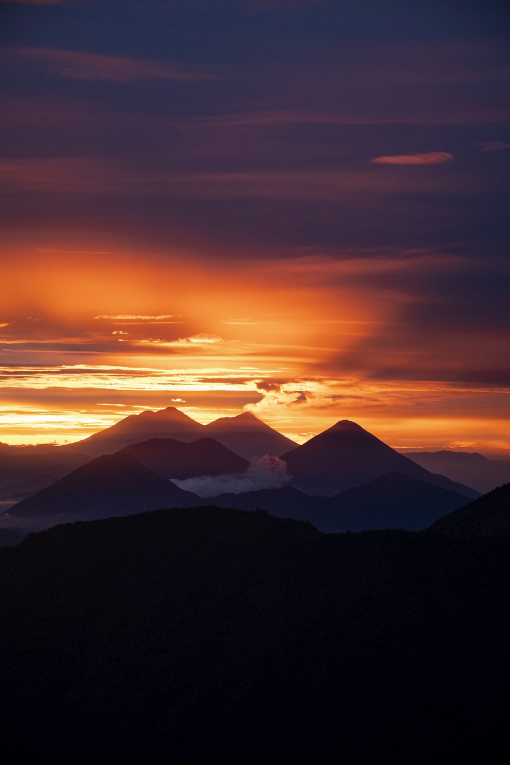 the sun is setting over a mountain range