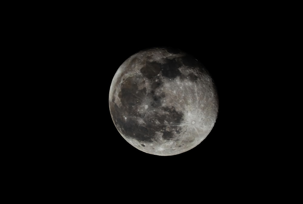 a full moon is seen in the dark sky