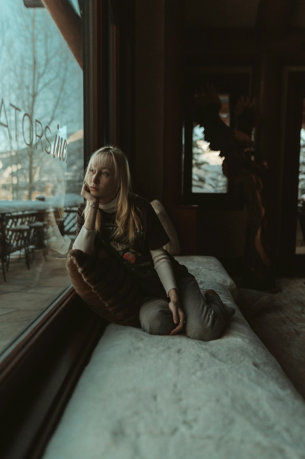 a girl sitting on a window sill looking out the window