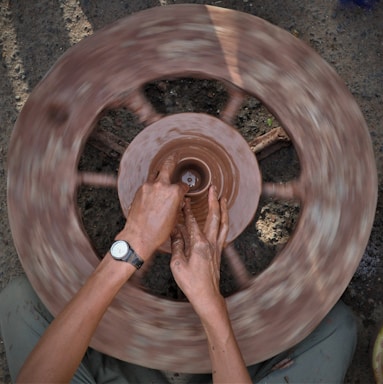 Close-up of hands shaping a ceramic bowl on a pottery wheel, with soft natural light.
