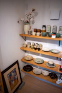A curated shelf displaying ceramics, books, and small plants.