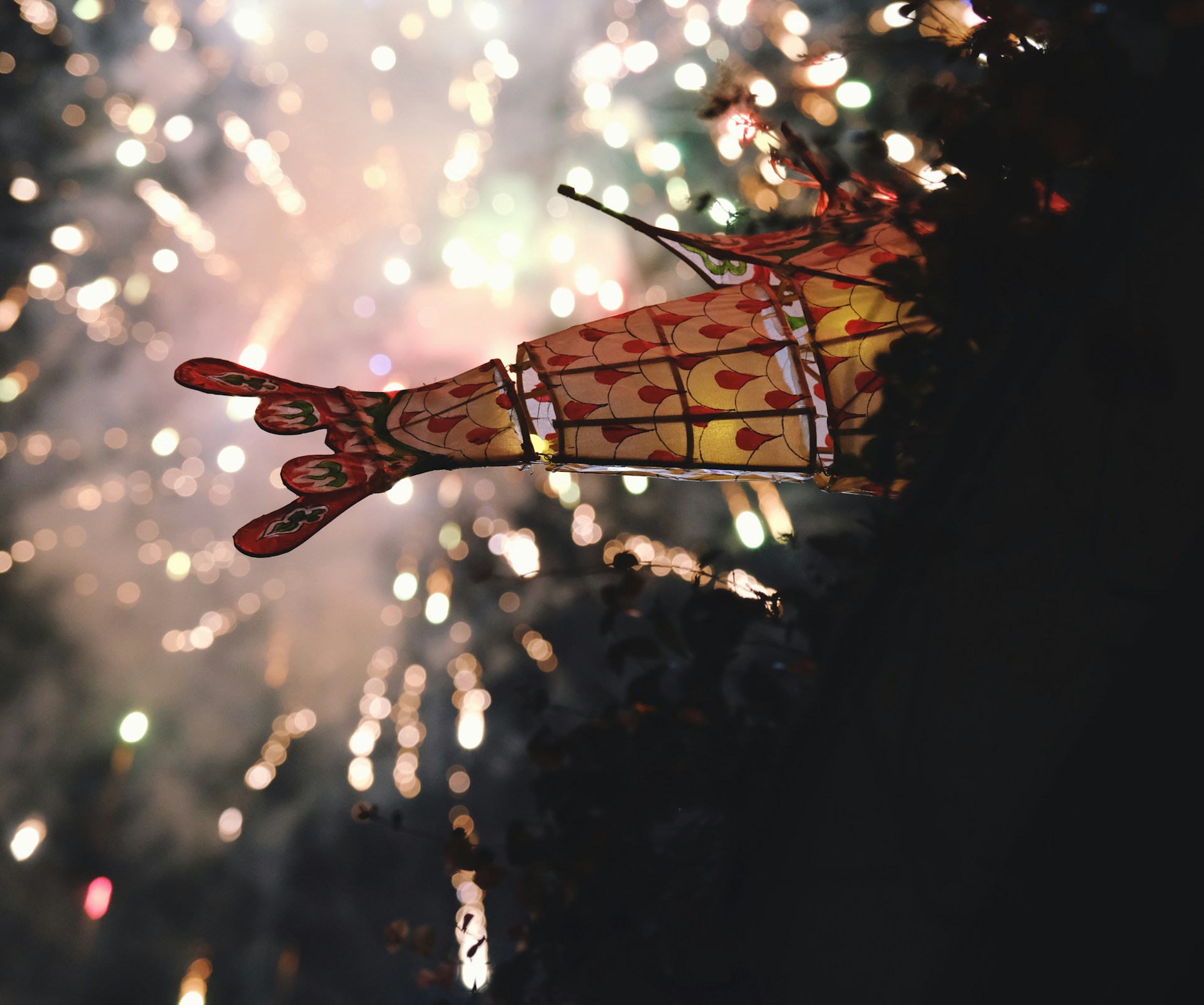 A festive scene with red lanterns and fireworks bursting in the night sky, evoking the lively spirit of the Spring Festival and the coin's celebration.