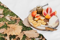 A sunlit picnic blanket spread with an assortment of dried fruits, nuts, and seeds nestled in glass jars.