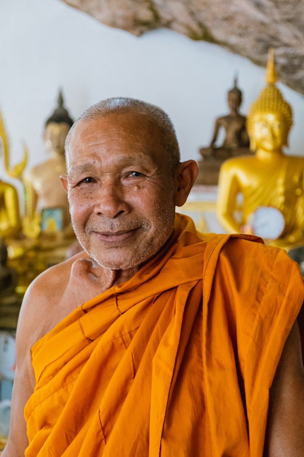 a man in an orange robe smiles at the camera