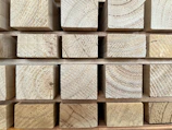 Stacked timber beams ready for a hands-on build project in a workshop.