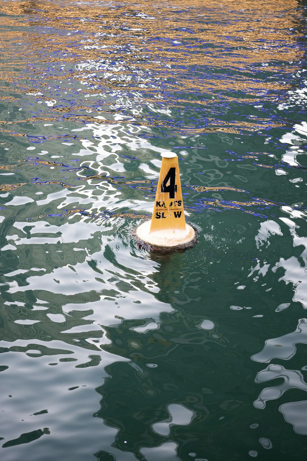 a yellow caution cone floating on top of a body of water
